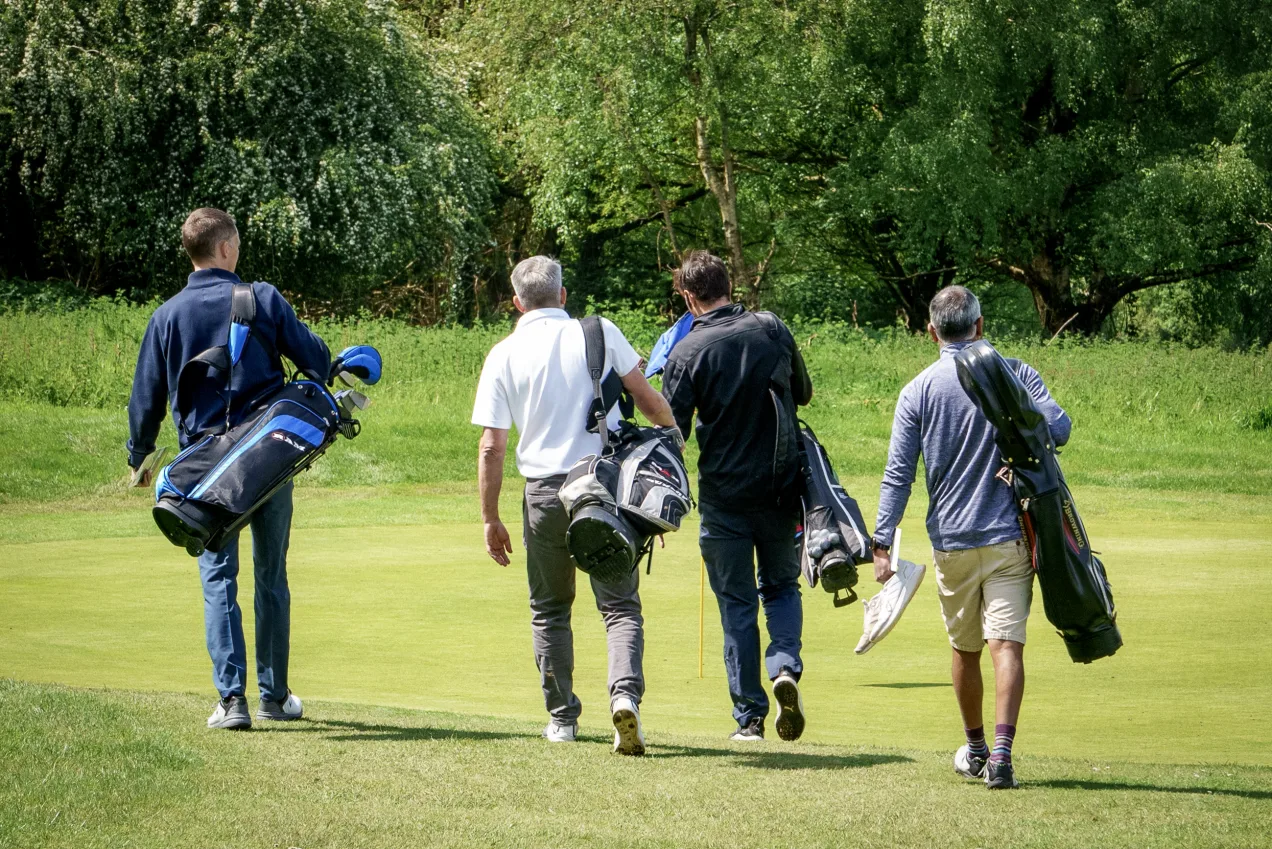 Four golfers walking down the fairway towards the green at a golf course in woking
