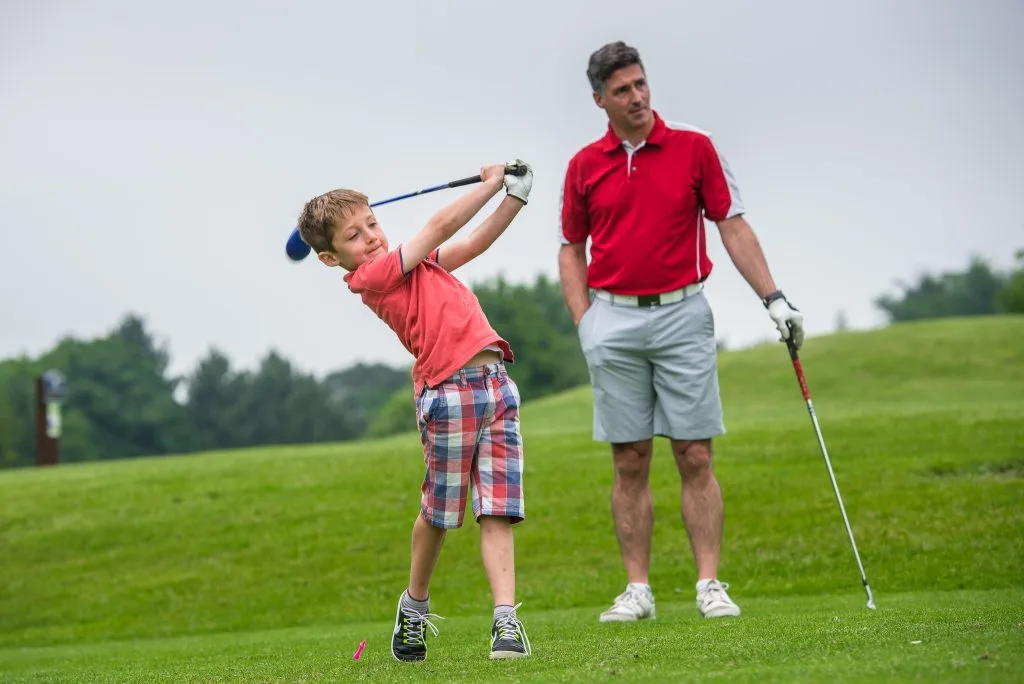 young man and his dad playing golf together at a short course in surrey