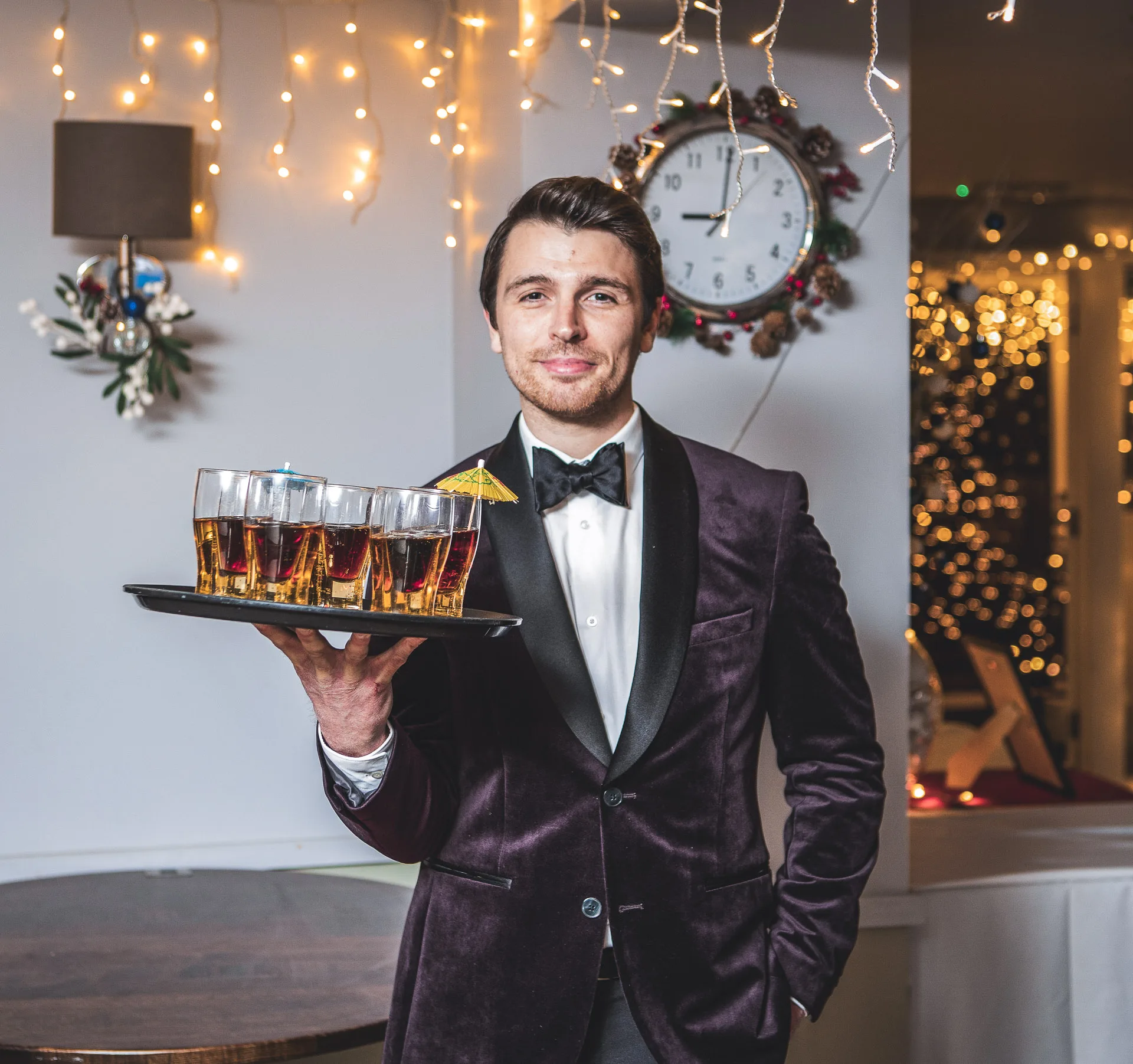 bar tender in velvet suit holding a tray of drinks at a christmas party venue in woking