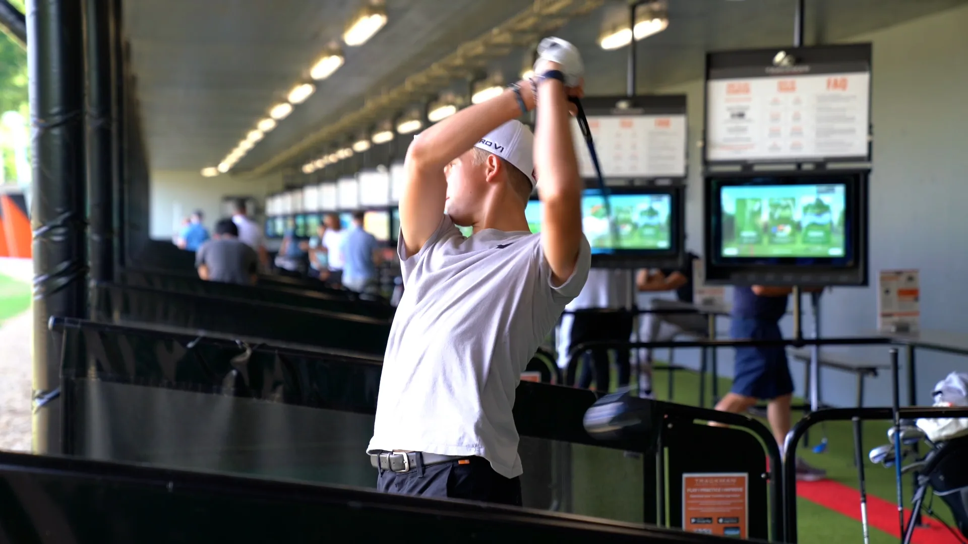 man hitting balls out of a large driving range in Surrey with launch monitor behind him