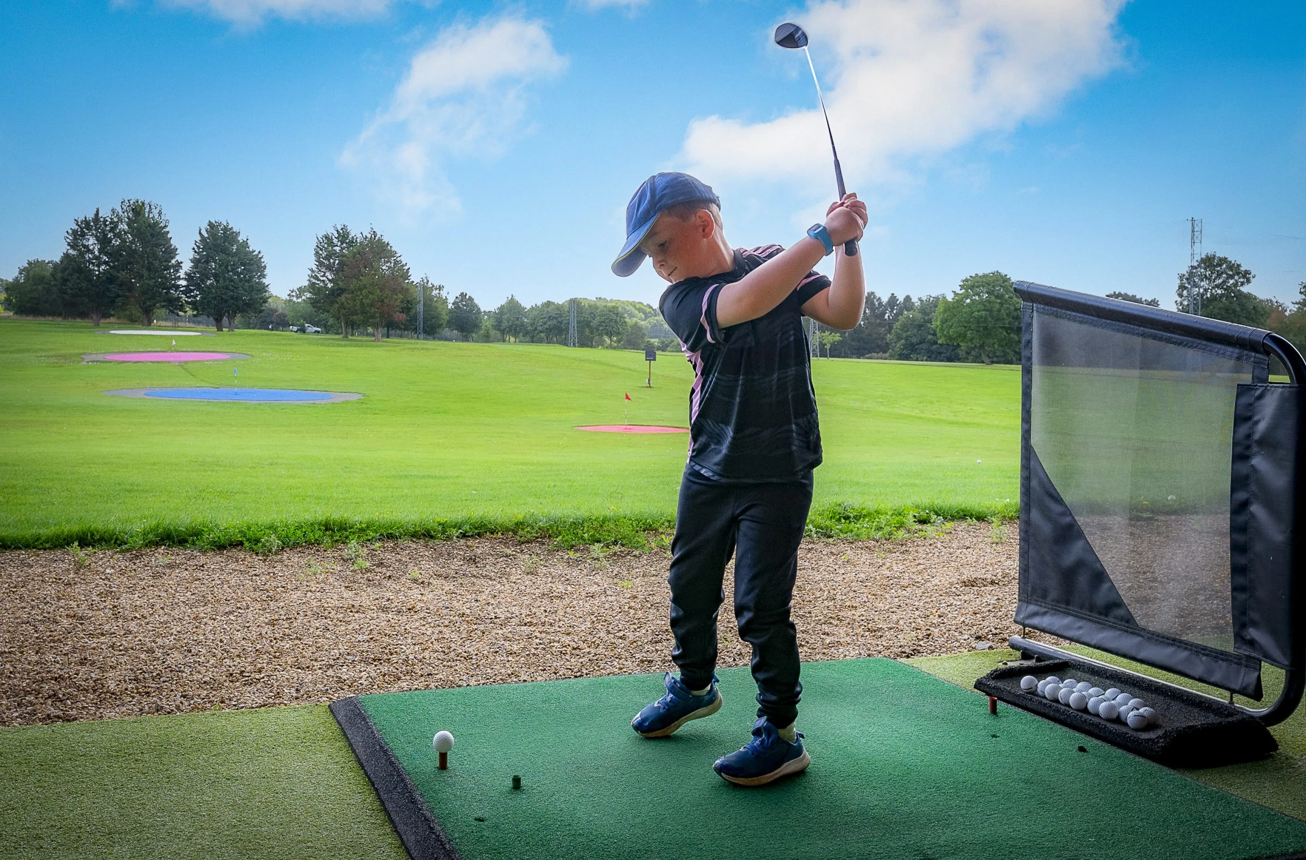 junior golfer hitting balls out of a driving range in Surrey