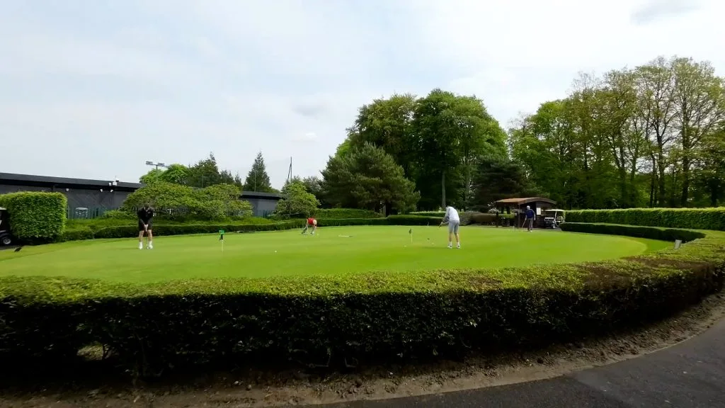 People putting on a practice green at a golf club in Woking.