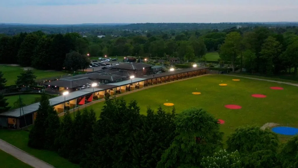 Floodlit golf driving range in Surrey seen from above, offering virtual golf and evening practice.