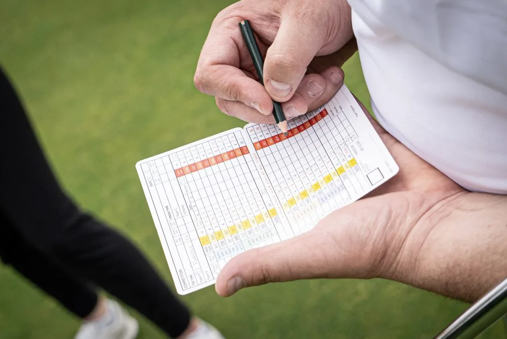 Man writing on a scorecard at a golf course in Woking.