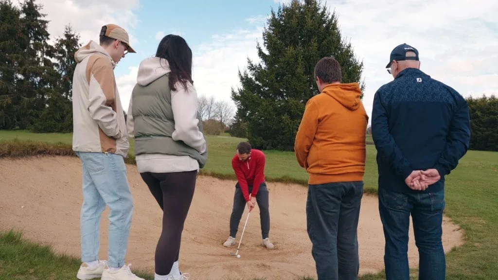 Golf pro demonstrating bunker shot during golf lessons in Woking on pathway to sgolf